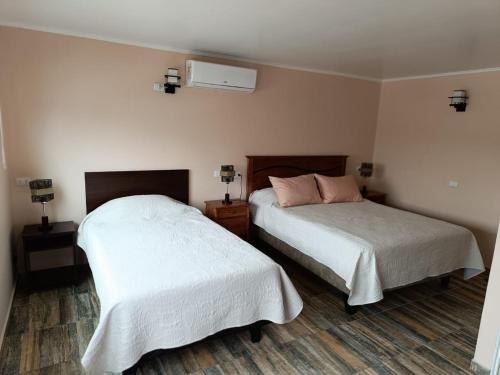 1 dormitorio con 2 camas con sábanas blancas en Cafetto Hostal en Caldera