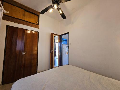 1 dormitorio con 1 cama y ventilador de techo en Dept.  completo a metros del mar en Villa Gesell
