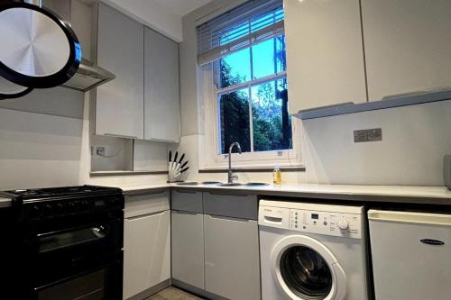 a kitchen with a washing machine and a window at Quaint 1BD Flat 5 mins from Emirates Stadium! in London
