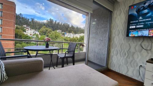 a room with a balcony with a table and a tv at 600 Excelente Vista panoramica,piscina,sauna,seguridad 24h,acojedor,confortable,Excellent panoramic view, swimming pool, private security 24h comfortable and cozy in Quito