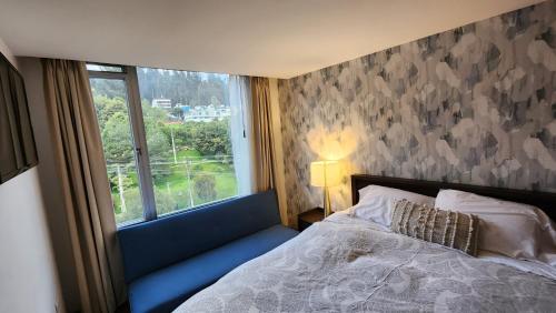 een slaapkamer met een bed en een raam met uitzicht bij invitin annabella's apartment in Quito