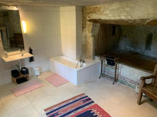 ein Badezimmer mit einer Badewanne und einem Waschbecken in der Unterkunft Maison de charme avec piscine in Orches