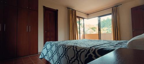 a bedroom with a bed and a large window at La Rivera Chamba Apartamento in Loja