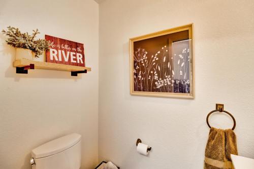 a bathroom with a white toilet and a picture at Cotter Home with Direct Access to White River! in Cotter