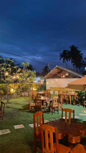 a restaurant with wooden tables and chairs at night at Pousada Yapara-Tyba in Japaratinga