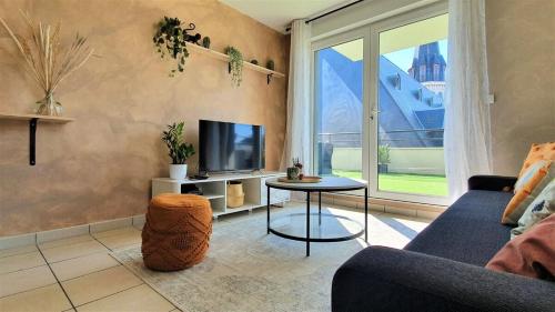 sala de estar con sofá, TV y mesa en Logement moderne et lumineux Terrasse et Parking, en Caen