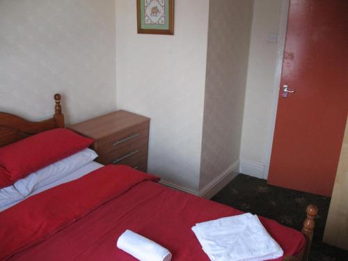 a bedroom with a red bed with two towels on it at Nevada Hotel in Blackpool