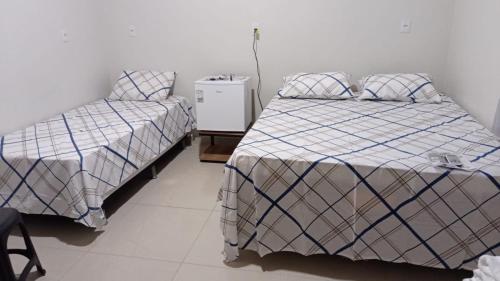 una camera con 2 letti singoli e un comodino di Maura oliveira a Boa Vista