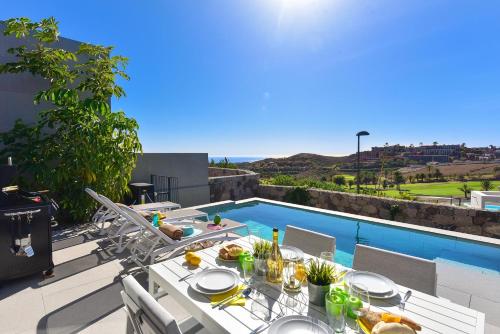 a table with food on it next to a swimming pool at Las Yucas 2 by VillaGranCanaria in Arguineguín