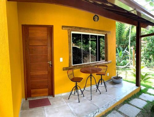 a yellow house with two chairs and a table on a patio at Segredo da alma in Sana