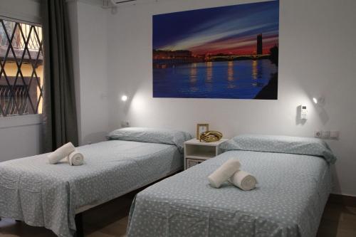 2 aparte bedden in een kamer met een schilderij aan de muur bij LUISAHOUSE, en el corazón de Sevilla y Triana in Sevilla