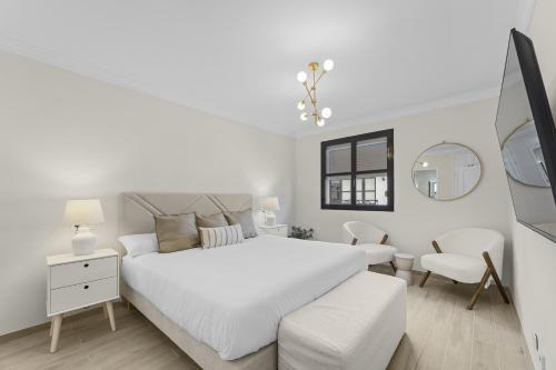 a white bedroom with a white bed and a chair at Casahost Guenia Beach Apartment in Arrecife