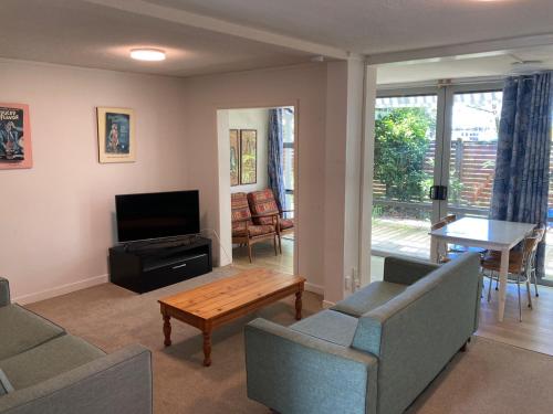 sala de estar con sofá, mesa y TV en City Towers Apartments, en Auckland