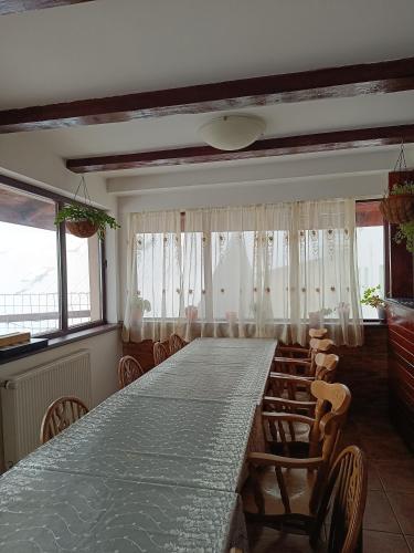 a long table in a room with chairs and windows at Pensiunea Tania in Ranca