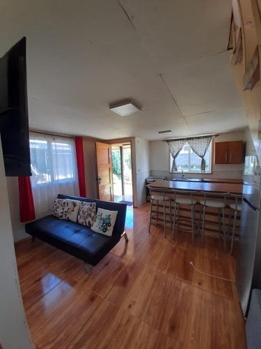 a living room with a black couch and a kitchen at Cabañas Emanuel in Chonchi