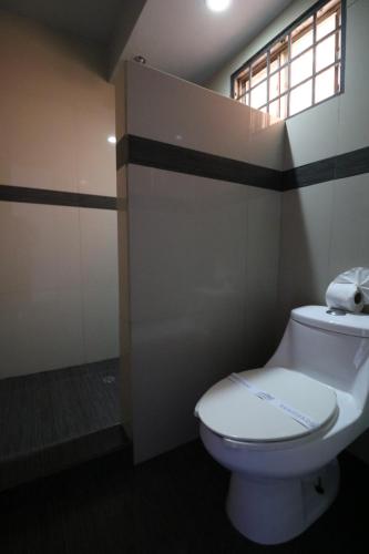 a bathroom with a white toilet and a window at Hotel Hacienda in Ensenada