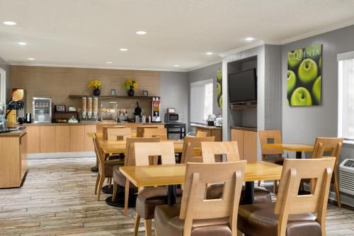 a restaurant with wooden tables and chairs and a kitchen at La Quinta by Wyndham Chicago Tinley Park in Tinley Park