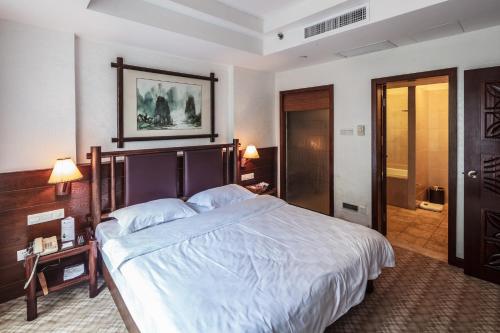 una camera da letto con un grande letto con lenzuola bianche di Longsheng Hot Spring Resort a Longsheng