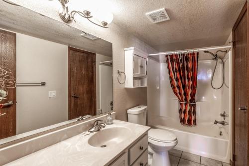 Un baño con lavabo, inodoro y espejo. en Grande View Condo: 3 Bedroom 2 Bathroom Townhome with a Game Room!, en Ruidoso