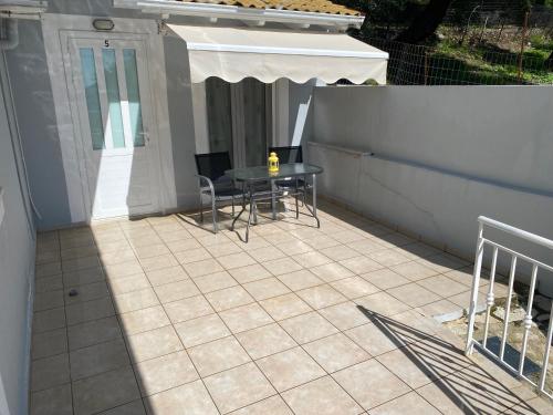 een patio met een tafel en stoelen en een parasol bij Home Apartments in Parga