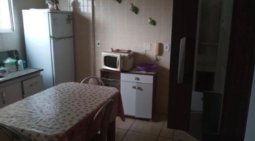 W kuchni znajduje się biała lodówka i kuchenka mikrofalowa. w obiekcie Mourão 5 w mieście Praia Grande
