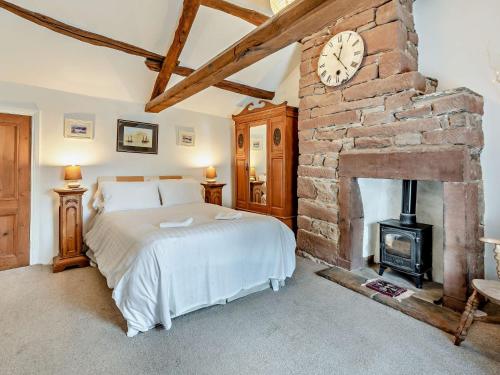 2 Bed in Kirkland SZ255 في Arlecdon: غرفة نوم مع سرير ومدفأة حجرية