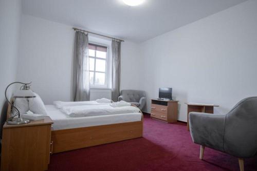 a bedroom with a bed and two chairs and a window at Hotel Zámeček Raspenava in Raspenava