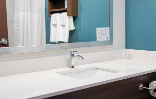 La salle de bains est pourvue d'un lavabo blanc et d'un miroir. dans l'établissement WoodSpring Suites Hudson Port Richey, à Hudson