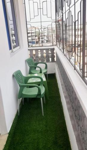 uma fila de cadeiras verdes num quarto com janelas em elegant luxury 2 bedroom mombasa wifi two balconies em Mombasa