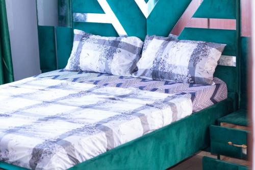 uma cama com um edredão verde e branco e almofadas em elegant luxury 2 bedroom mombasa wifi two balconies em Mombasa