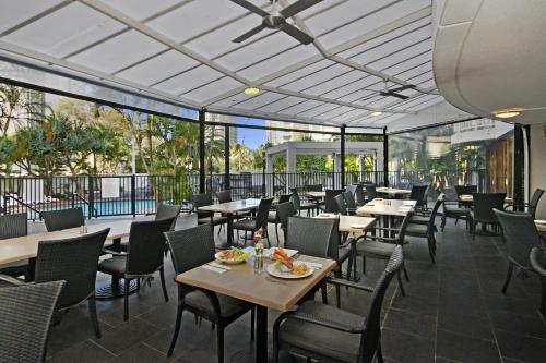 a dining room with tables and chairs and windows at Sovereign on the Gold Coast in Gold Coast