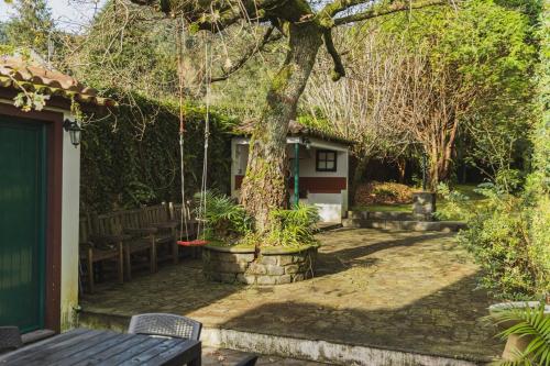 a patio with a tree and a table and bench at O Moinho (Furnas Hot Springs) in Furnas