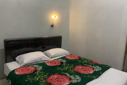 a bed with a green blanket with red roses on it at Mozza guest house in Klaten