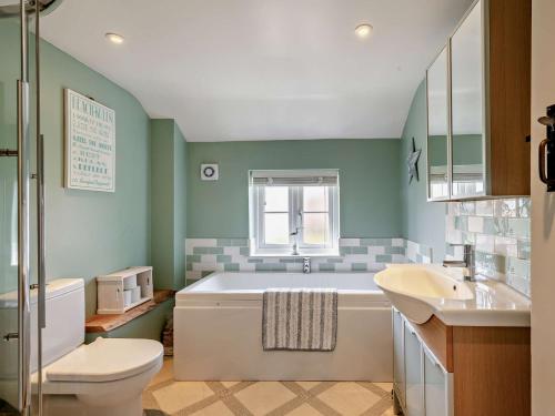 a bathroom with a tub and a toilet and a sink at 4 Bed in Sea Palling 89919 in Sea Palling