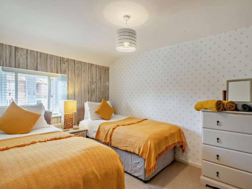 a bedroom with two beds and a dresser at 4 Bed in Sea Palling 89919 in Sea Palling