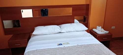een bed met witte lakens en kussens in een kamer bij Hotel Allison in Huacho