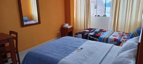 een hotelkamer met 2 bedden en een spiegel bij Hotel Allison in Huacho