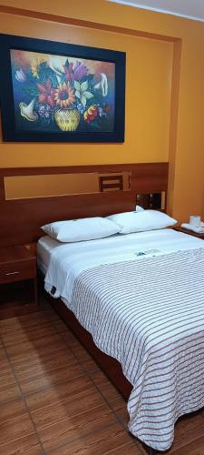 een slaapkamer met een bed met een schilderij aan de muur bij Hotel Allison in Huacho