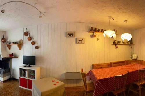 ペーイオ・フォンティにあるGrazioso appartamento nel cuore della Val di Soleのテーブルとテレビのあるダイニングルーム