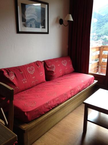 a red couch in a room with a window at Les Chalets Valoria - 2 Pièces pour 4 Personnes 44 in Valloire