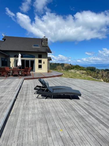 a large wooden deck with a patio and a house at Parautane Lodge in Nelson