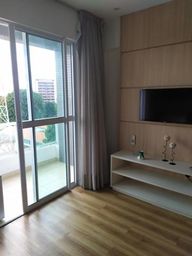 sala de estar con TV y puerta corredera de cristal en Studio Moderno bem localizado en Feira de Santana