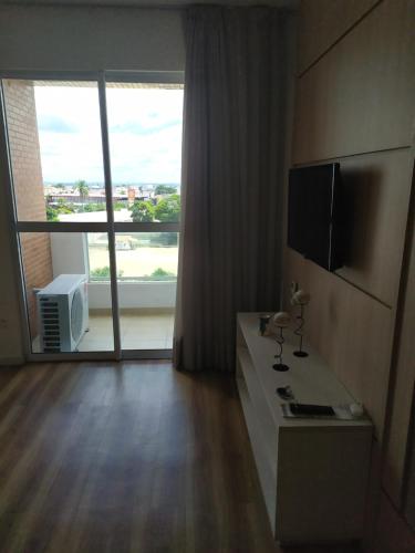 a living room with a large window and a television at Studio Moderno bem localizado in Feira de Santana