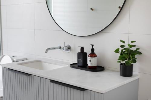 een badkamer met een wastafel en een spiegel bij Topdeck at Snelling Beach in Stokes Bay