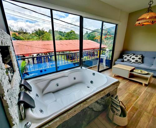 a bath tub in a room with a large window at Habitacion Deluxe 2 con Jacuzzi a 20 mt del parque in Salento