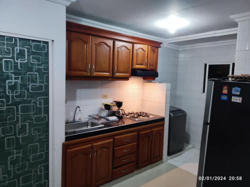 cocina con armarios de madera y nevera negra en Bonito apartamento en Cartagena con garaje gratuito en Cartagena de Indias