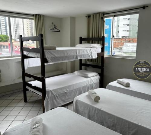 a room with three bunk beds and a window at Hotel América Praia in Recife