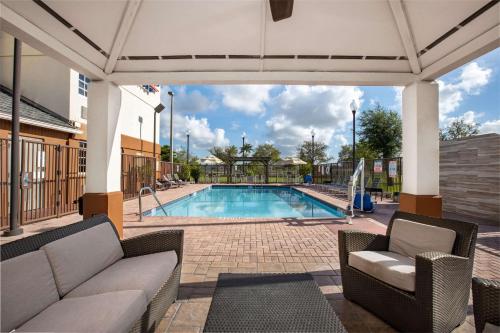 a swimming pool with a couch and chairs in a patio at Sonesta Simply Suites Miami Airport Doral in Miami