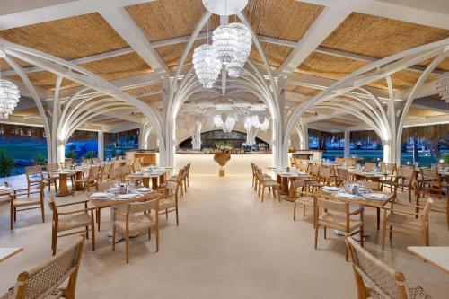 a banquet hall with tables and chairs and chandeliers at Cullinan Belek in Belek