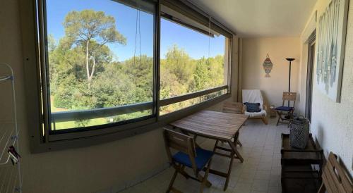 Cette chambre dispose d'une table en bois et d'une grande fenêtre. dans l'établissement Résidence Olivier - APPARTEMENT FRONT DE MER DANS DOMAINE AVEC PISCINE MAE-8764, à Six-Fours-les-Plages